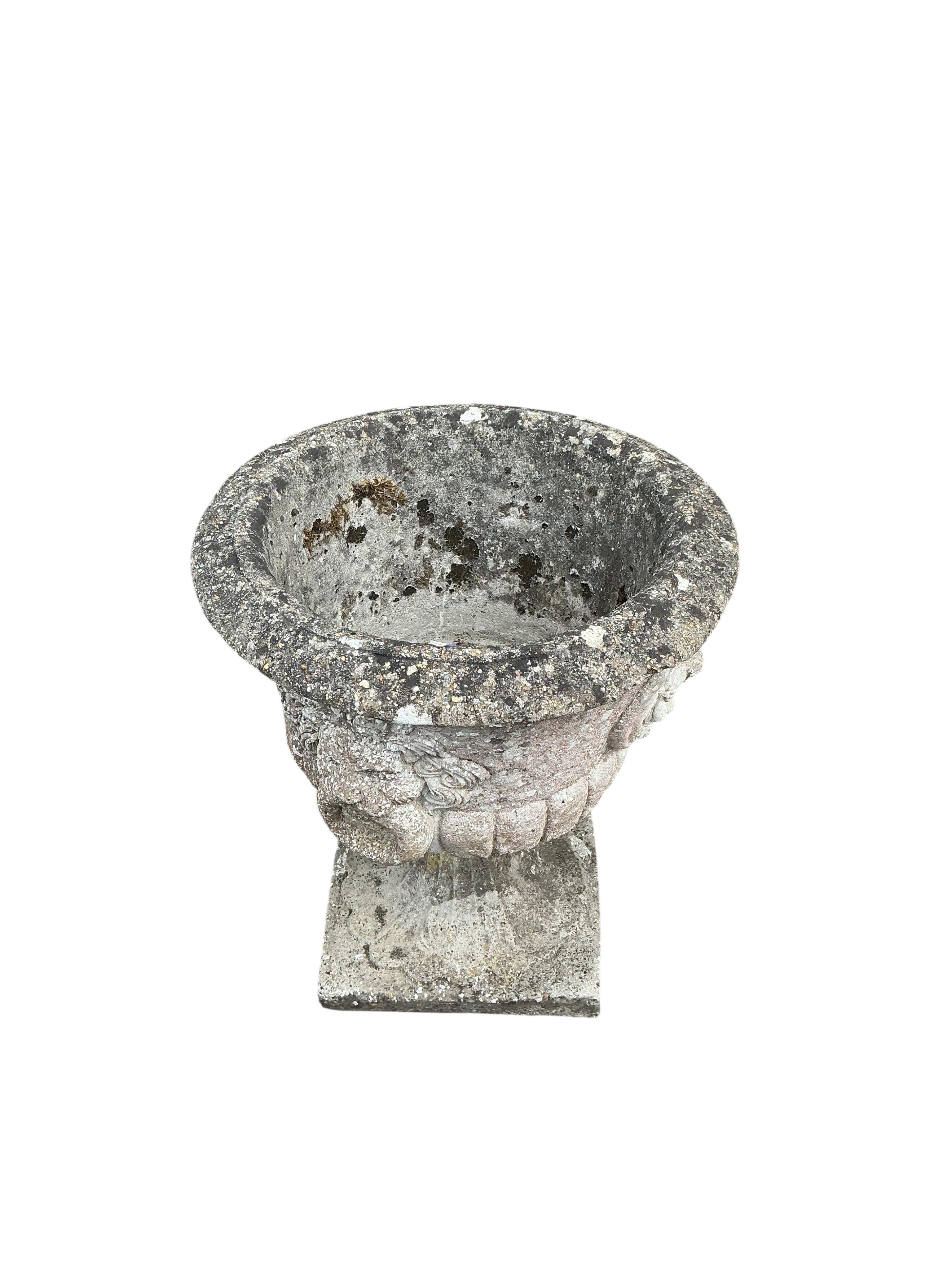 A pair of circular reconstituted stone garden urns with moulded lion mask ring decoration, diameter 53cm, height 60cm